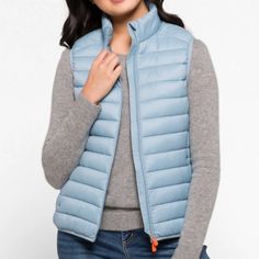 This Puffer Vest Is A Spring Wardrobe Staple. Made From Lightweight Nylon With Animal-Free Plumtech Padding, This Iconic Style Features A Standing Collar, Secure Zipped Pockets And Lycra Trims At The Cuffs And Hem. The Signature Orange Zip Pullers Add A Distinctive Touch. Light Blue Puffer Vest Outfit, Lightweight Casual Spring Outerwear, Lightweight Casual Outerwear In Solid Color, Spring Nylon Outerwear, Spring Solid Nylon Outerwear, Spring Travel Fitted Outerwear, Fitted Spring Travel Outerwear, Beige Puffer, Red Puffer Coat