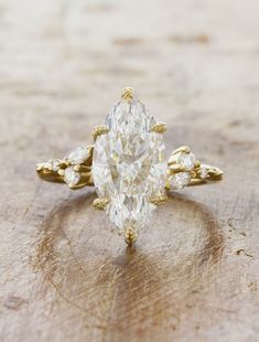 an oval shaped diamond ring with three small diamonds on the band and side stones in yellow gold