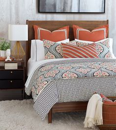 a bed with an orange and white comforter on it next to a night stand