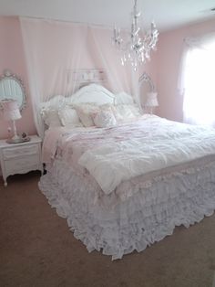 a white bed sitting in a bedroom next to a window and a chandelier