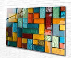 a multicolored glass wall hanging on a brick wall with white bricks in the background