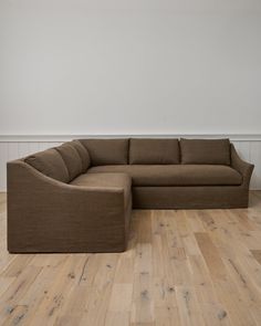 a brown couch sitting on top of a hard wood floor next to a white wall