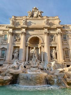 an ornate building with statues and fountains in front