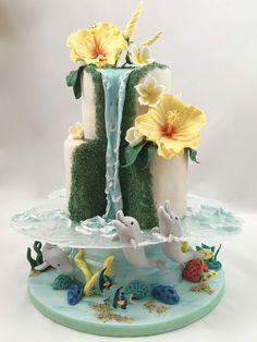 a three tiered cake decorated with flowers and water features the letter e on top