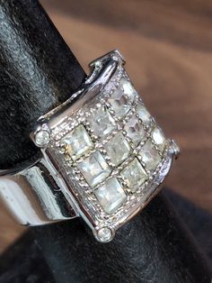 a diamond ring is sitting on top of a black piece of leather with a wooden surface in the background