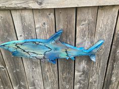 a blue fish is hanging on the side of a wooden fence