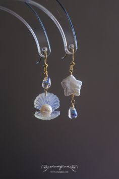 ---- Welcome to CiaoQiao Shop ----- These stunning, sea-inspired dangle earrings crafted with delicate care, each earring features a shimmering pearl nestled in a lustrous shell, complemented by a cascade of blue crystal droplets that reflect the tranquil hues of the sea. The iridescent glow of the shells and pearls brings a natural, serene beauty to any ensemble. Perfect for beach weddings, seaside events, or adding a splash of oceanic charm to your everyday wear. Length including hooks: 1 1/2" | 3.8cm Please note: natural pearls will have flaws and each is unique. Tips for making your Jewelry last longer - Remove your jewelry before you swim in chlorine or salt water. - Remove your jewelry before participating in activities that will cause you to sweat a lot. - Wait to put on your jewelr Luxury Ocean-inspired Earrings For Gift, Ocean-inspired Dangle Pearl Drop Jewelry, Dangle Shell Pearl Earrings, Ocean-inspired Pearl Drop Dangle Jewelry, Ocean-inspired Dangle Single Earring, Ocean-inspired Single Dangle Earring, Ocean-inspired Dangle Shell Earrings, Ocean-inspired Shell Dangle Earrings, White Ocean-inspired Dangle Earrings