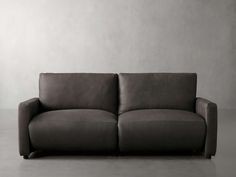 a gray couch sitting on top of a floor next to a white wall in an empty room