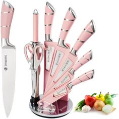 a pink knife holder with several knives in it and some vegetables next to it on a white background