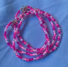 pink and white beaded necklace with silver clasp on blue fabric background, closeup