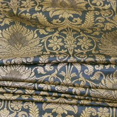 a blue and gold fabric with an intricate design on it's side, folded in half