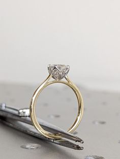 a diamond ring sitting on top of a pair of scissors