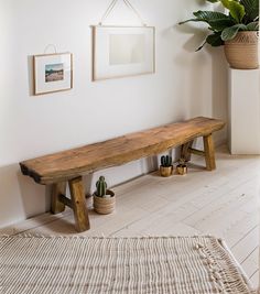 a wooden bench sitting in the middle of a room next to a potted plant