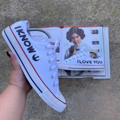 someone is holding their tennis shoes in front of a magazine with an image of princess leia on it