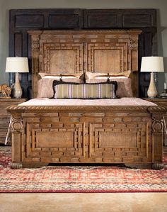 a large wooden bed sitting on top of a carpeted floor next to two lamps