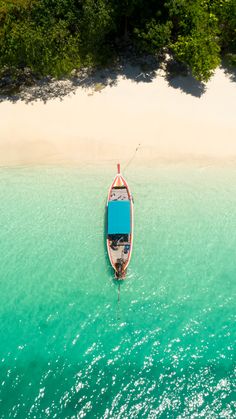 an aerial view of a boat in the water near a sandy beach and forested area