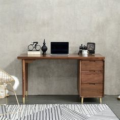 a wooden desk with a laptop on top of it next to a chair and rug