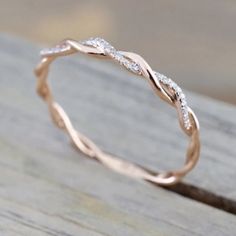 a rose gold wedding band with white diamonds on the inside and outside, sitting on top of a piece of wood