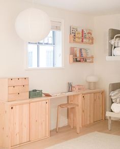 a white room with wooden furniture and shelves on the wall, along with a large window