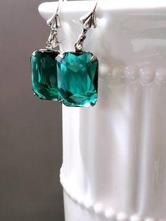 I love the clean simple lines and the sheer emerald green color of these Art Deco style estate earrings. They feature emerald green octagon rhinestone beads and silver plated leverback ear wires. These elegant earrings measure 1 1/4 inches long. Perfect for everyday or evening. ABOUT THIS COLLECTION What are the three style essentials Jazz Age flappers like Clara Bow, Louise Brooks, and Zelda Fitzgerald have in common? Red lipstick, bobbed haircuts, and fabulous dangle earrings. My Flapper Colle Green Art Deco Drop Earrings, Elegant Rectangular May Birthstone Earrings, Elegant Rectangular Emerald Earrings For May Birthstone, Elegant Green Crystal Earrings For Pierced Ears, Green Crystal Earrings For Pierced Ears, Formal Rectangular Earrings With May Birthstone, Elegant Green Crystal Earrings With Ear Wire, Art Deco Green Jewelry For Pierced Ears, Vintage Style Emerald Drop Earrings