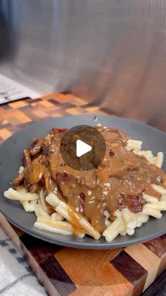 a plate with some meat and gravy on top of it next to french fries