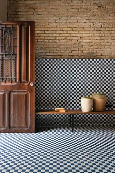 a wooden door sitting next to a black and white checkered floor with potted plants on it