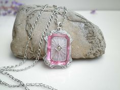 "Up for sale is this beautiful pink camphor glass sterling silver pendant and link necklace. The pendant is signed H with two triangles one on each side of the H and I believe this is from the 1920's.  The link chain is signed D&C for Daggett & Clap Co.,  from era 1896 to 1915 and it features a tube catch clasp from that time.   *Metal Purity: Sterling Silver (tested) *Gemstone:Camphor Glass *Pendant Width:24.8mm tall ∣ 17.2mm wide *Necklace Length: 17\"  Long   *Chain Width:2mm wide *Weight: Pink Vintage Charm Pendant Jewelry, Elegant Pink Locket Jewelry, Pink Engraved Necklace For Gift, Antique Hallmarked Pink Jewelry, Antique Pink Hallmarked Jewelry, Vintage Pink Gemstone Necklace, Pink Antique Hallmarked Jewelry, Pink Sterling Silver Necklace For Formal Occasions, Elegant Pink Jewelry With Engraving