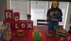 a red table topped with lots of cakes and candy boxes covered in frosting next to a window