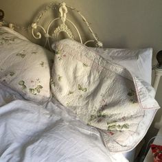 an unmade bed with white linens and pillows on top of the headboard