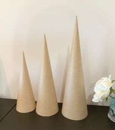 three small cones are sitting on a table next to a vase with flowers