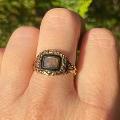 a close up of a person's hand holding a ring with a stone in it