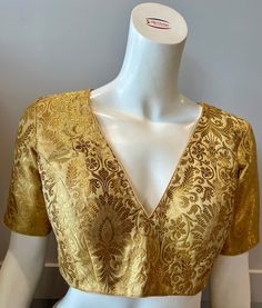 A golden color blouse Product details Fabric - silk blend Bust size 40" Waist 32" sleeve length 10" Can be tailored to fit 42" For extra charges Festive V-neck Evening Blouse, Elegant V-neck Blouse For Festive Occasions, Elegant Festive V-neck Blouse, Elegant V-neck Top With Zari Work, Elegant V-neck Tops With Zari Work, Traditional Gold V-neck Tops, Gold V-neck Blouse For Wedding, Gold V-neck Bollywood Blouse Piece, Fitted V-neck Blouse With Zari Work