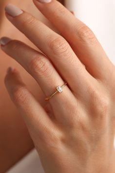 a woman's hand wearing a gold ring with a small diamond on the middle