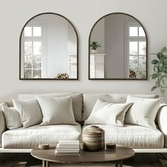 a living room with two mirrors on the wall and a couch in front of it