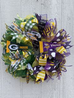 the green bay packers football wreath is hanging on a white wooden wall with purple and yellow ribbons