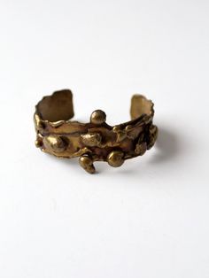 "This is a 1960s vintage brutalist brass cuff. The hand-crafted piece features intricate cast detailing with a striking patina.  CONDITION In good condition with wear consistent with age and use. MEASUREMENTS Length:  5.5\"  ...  14 cm Width:  1.25\"  ...  3.2 cm SHOP MORE CUFFS from 86 Vintage https://www.etsy.com/shop/86Vintage86/search?search_query=cuff+jewelry 111598" Vintage Gold Bracelets With Oxidized Finish, Antique Bronze Brass Cuff Bracelet, Hand Cast Bronze Metal Cuff Bracelet, Brutalist Brass Jewelry In Bronze, Brutalist Bronze Brass Jewelry, Antique Finish Brass Cuff Bracelet, Bronze Hand Forged Metal Cuff Bracelet, Bronze Antique Finish Cuff Bracelet Bangle, Hand Forged Bronze Metal Cuff Bracelet