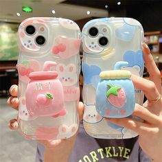 two people holding up cell phones with cartoon characters on them, one is pink and the other is blue