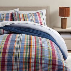 a bed with colorful plaid comforter and pillows