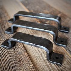 three metal brackets are sitting on a wooden surface