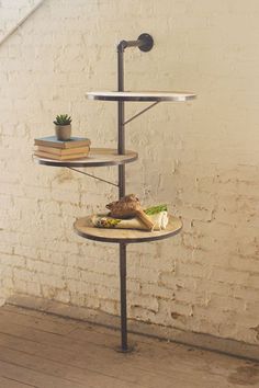 a three tiered shelf with books on it in front of a white brick wall