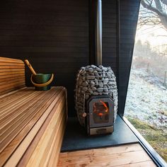 a wood burning stove sitting on top of a wooden floor next to a bench and window