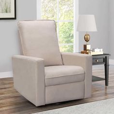 a living room with a gray chair and lamp on the side table in front of a window