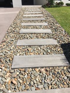 there are several stepping stones on the side of this driveway that is lined with grass