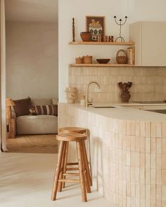 a kitchen with a wooden stool next to a counter top and shelves on the wall