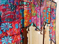 colorful cloths are hanging on a wooden fence