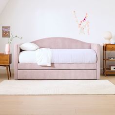 a pink daybed with white sheets and pillows