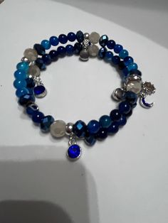 Introducing our stunning Blue Agate Memory Wire Bracelet with Sun, Moon, and Star Charm! This unique bracelet features beautiful blue agate beads that are known for their calming and balancing energies. The addition of the sun, moon, and star charms adds a touch of celestial beauty to this piece. Perfect for those who love the mystical and magical, this bracelet is the perfect accessory to add a pop of color and whimsy to any outfit. Handcrafted with care and attention to detail, this bracelet is a true statement piece that is sure to turn heads. Add a touch of celestial magic to your jewelry collection with this enchanting bracelet! Blue Beaded Agate Bracelets, Blue Moonstone Beaded Bracelets With Gemstone Beads, Handmade Blue Agate Bracelets, Blue Agate Beaded Bracelets For Gift, Handmade Blue Moonstone Beaded Bracelets, Bohemian Blue Agate Bracelets, Blue Spiritual Beaded Bangle Bracelets, Spiritual Blue Beaded Bangle Bracelets, Spiritual Blue Beaded Bangle Bracelet