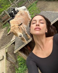 a woman standing next to a goat on top of a wooden ramp