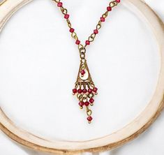 This lovely necklace features, red ruby tiny Swarovski crystals, a gorgeous, vibrant red crystal made by Swarovski, renowned for their exceptional quality and sparkle. Handcrafted with brass elements, a durable and attractive metal alloy that provides a warm, base for the necklace, characterized by a delicate multi-strand design pendant that resembles a chandelier, adding depth, visual interest and glamour to every day wear.  This necklace is perfect for those who love understated yet stylish ac Red Crystal Necklace For Gift, Chandelier Necklace, Ruby Crystal, Necklace Red, Vintage Style Jewellery, Brass Chandelier, Lovely Necklace, Jewelry For Her, Red Crystals