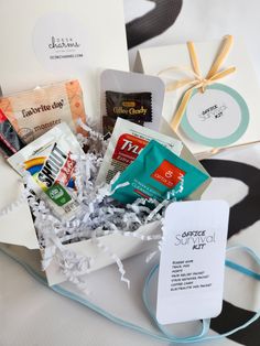 an assortment of snacks in a gift box on a white tablecloth with blue ribbon